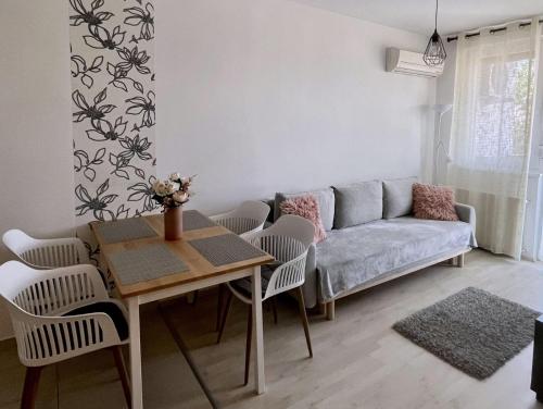 a living room with a couch and a table and chairs at Ada Wellness Apartman Siófok in Siófok