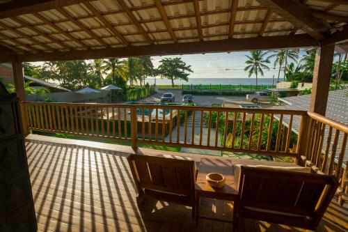 a balcony with two chairs and a table and the ocean at Tropical Beach in Porto Seguro