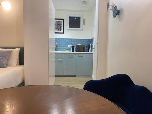 Cette chambre comprend une table, un lit et une cuisine. dans l'établissement Cosy studio a 20 min del Arco del Triunfo en RER, à Maisons-Laffitte