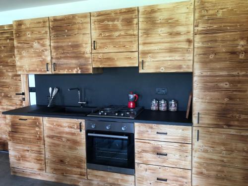 a kitchen with wooden cabinets and a stove at Baita Poira in Mello