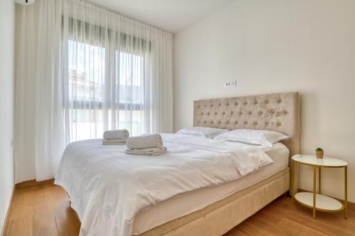ein weißes Schlafzimmer mit einem großen Bett und einem Laptop darauf in der Unterkunft Helena apartment Tivat in Mrčevac