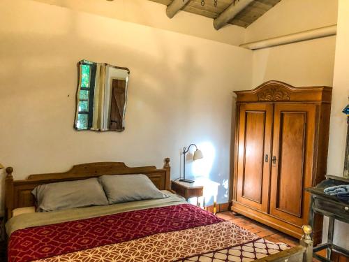 1 dormitorio con cama y espejo en la pared en Casa de campo - retiro con encanto en las sierras en Minas