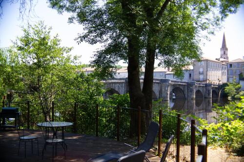 a table and chairs next to a river with a bridge at Pont Vieux Chambres et Gites in Confolens