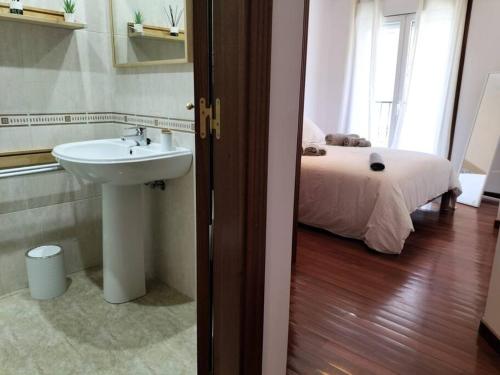 a bathroom with a sink and a bed in a room at Precioso apartamento renovado in Ribeira