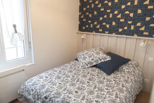 um quarto com uma cama com um edredão e uma almofada em Le BAC FLEURI em Trouville-sur-Mer