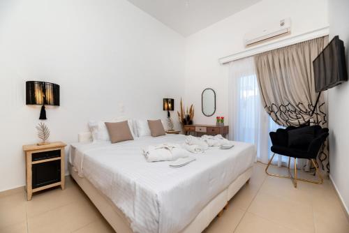 a bedroom with a large white bed and a television at Queen of Santorini in Karterados