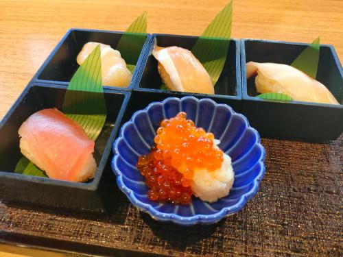 a tray of sushi with a bowl of sauce at Dormy Inn Tokyo Hatchobori Hot Spring in Tokyo