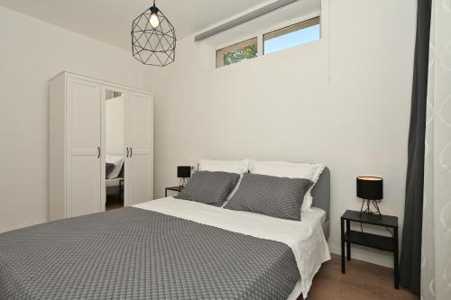 a white bedroom with a bed and a window at Apartment Relax near Split with Jacuzzi in Srinjine