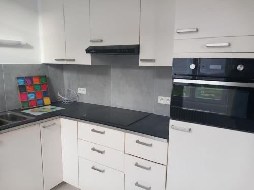 a kitchen with white cabinets and black appliances at Gite 7pers 3 chambres in Bouvincourt-en-Vermandois