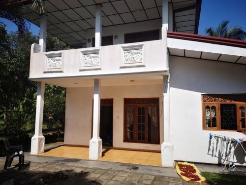 Dieses weiße Haus verfügt über eine Veranda und einen Balkon. in der Unterkunft Sithu Guesthouse in Bentota