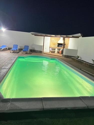 una piscina por la noche con 2 sillas azules en Villa linda, en Playa Blanca