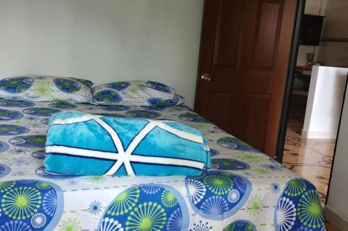 a bed with blue and white sheets and pillows at Hermosa casa familiar in La Tebaida