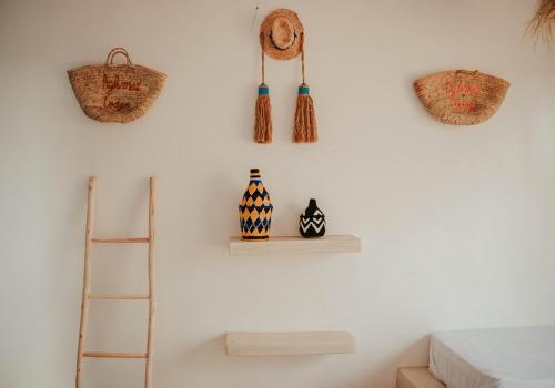 a white wall with baskets and vases and a ladder at Aghmat Lodge Guest house in Marrakech