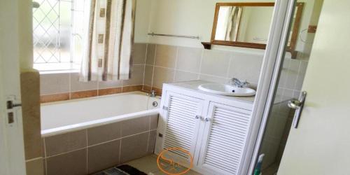 a bathroom with a tub and a sink and a bath tub at Slee Guest House in Howick