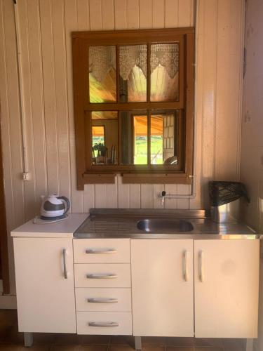 uma cozinha com um lavatório e uma janela em Sítio Rota das Araucárias em Urupema