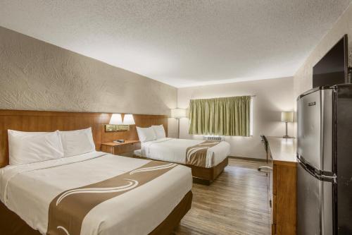 Habitación de hotel con 2 camas y nevera. en Rodeway Inn en Grand Rapids