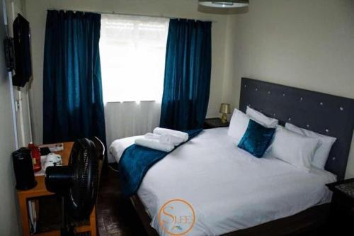 a bedroom with a bed with blue curtains and a window at Slee Guest House in Howick