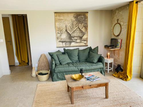 a living room with a green couch and a table at Gîte verveine bain nordique jacuzzi l écrin de verdure chinon in Ligré