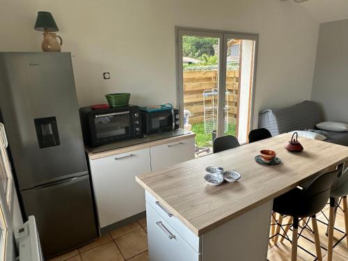 Il comprend une cuisine équipée d'un réfrigérateur et d'une table avec un four micro-ondes. dans l'établissement Petite maison plein pied jardin, à Soorts-Hossegor