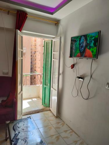 a room with a tv on a wall with a window at Miami furnished apartment next to Khaled Bin Al Waleed in Alexandria