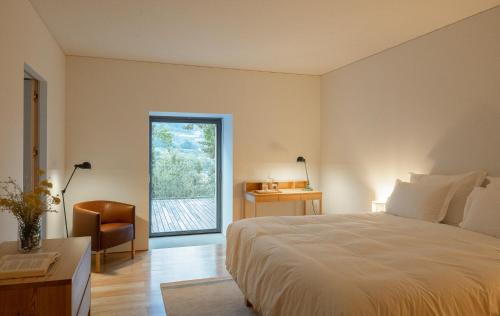 a bedroom with a bed and a chair and a window at Quinta do Outeiro 1598 in Ponte da Barca