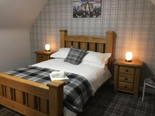 a bedroom with a wooden bed with two night stands at Glenshee Guest House in Golspie