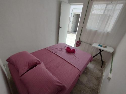 a bedroom with a pink bed with a red bow on it at 777 LENDERMAN HoSTaL 777 in Cancún