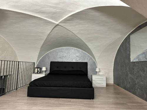una camera con letto nero in una stanza con soffitti curvi di Giordana house a Catania