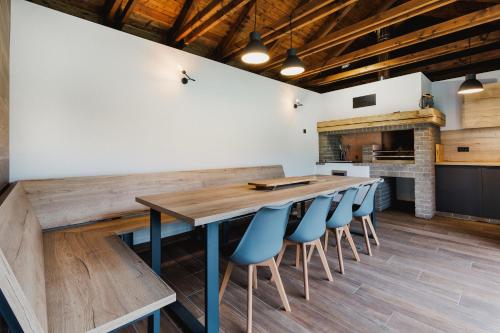 a kitchen with a large wooden table and blue chairs at Vila Grín in Mýto pod Ďumbierom