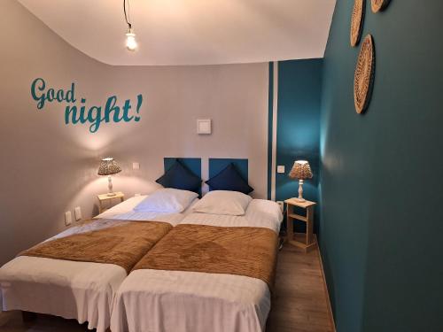 a bedroom with a bed with a good night sign on the wall at Gîte La Forge, ouvert en 2016. in Lierneux