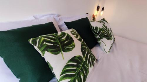 Una cama blanca con 4 almohadas verdes. en Villa da Serra, en Alto Paraíso de Goiás