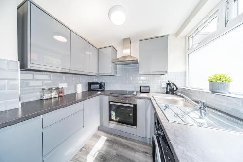 una cocina con armarios blancos y fregadero en Hosted By Ryan - Huge 4 Bedroom House en Liverpool