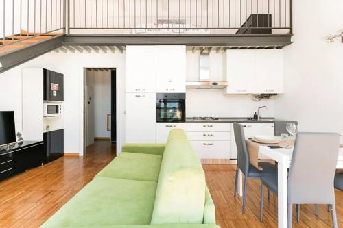 a living room with a green couch and a kitchen at Luxury Loft a Milano - Design esclusivo e comfort moderno in Milan
