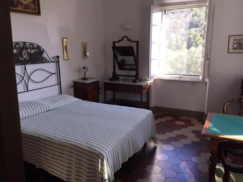 a bedroom with a bed and a desk and a window at Villa Sant'Antonio con ampio giardino a due passi dal mare in SantʼAnna