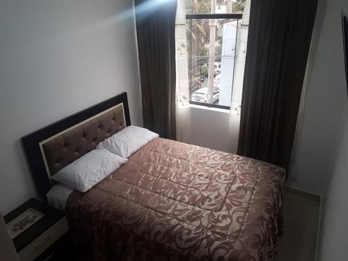 a bedroom with a bed with a brown bedspread and a window at Queen's Residence VIP in Tacna