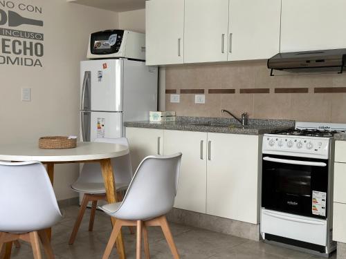 a kitchen with white cabinets and a table with chairs at Apartments Biritos in Godoy Cruz