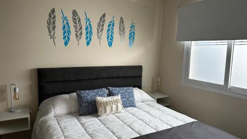 1 dormitorio con cama blanca y almohadas azules en Apartments Biritos en Godoy Cruz