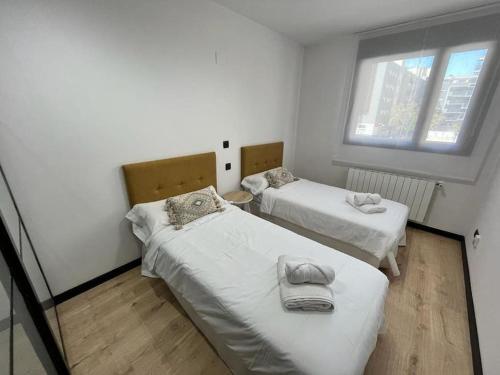 twee bedden in een kleine kamer met een raam bij El rincón de Martín en Huesca in Huesca