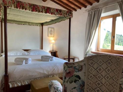 a bedroom with a canopy bed and a chair at Podere La Paolina in Montefollonico