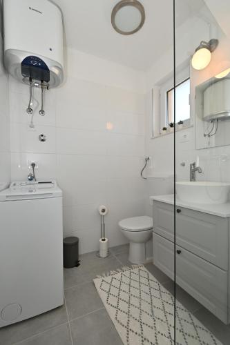 a white bathroom with a toilet and a sink at Romantic Escape With Private Hot Tub Near Split in Žrnovnica