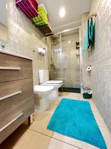 a bathroom with a toilet and a shower with a blue rug at Mama Yumbo in Playa del Ingles