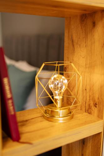 a gold clock on a wooden shelf next to a book at ENERGIE Дизайнерська стильна квартира в новому ЖК in Ternopilʼ