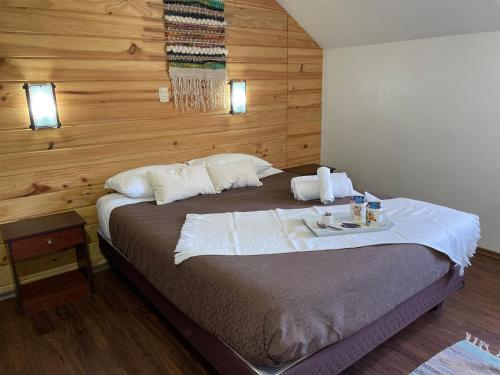 1 dormitorio con 1 cama grande y pared de madera en 7 Arriendo Habitación doble con Baño Privado de Ex Hotel en Puerto Varas
