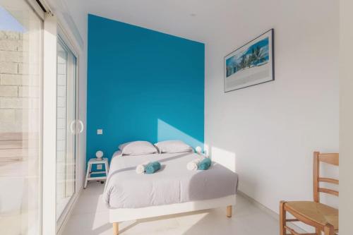 een slaapkamer met een bed met een blauwe accentmuur bij Charmante maison vue sur mer proche Carnac in Plouharnel