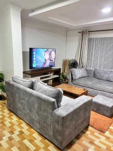 een woonkamer met 2 banken en een flatscreen-tv bij Ruyer one bedroom in Kisumu