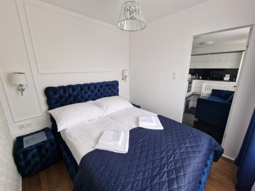 een slaapkamer met een blauw bed en een spiegel bij Apartament Helenka in Hajnówka