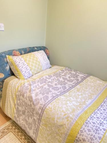 a bed with a comforter and pillows on it at Your Cosy and Welcoming HomeStay!! in Ilford