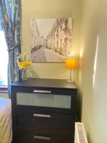 a bedroom with a dresser with a picture on the wall at Your Cosy and Welcoming HomeStay!! in Ilford