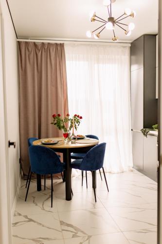 a dining room with a table and blue chairs at ENERGIE Дизайнерська стильна квартира в новому ЖК in Ternopilʼ