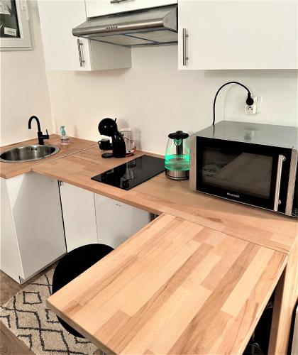 - une cuisine avec un comptoir en bois et un four micro-ondes dans l'établissement studio au cœur Montmartre, à Paris